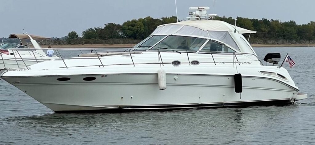 White cabin cruiser boat on calm water, flying a small American flag at the stern.